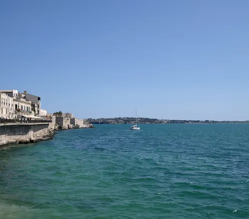 Cyan water in Sicily with a blue-green hue distinct from the sky.